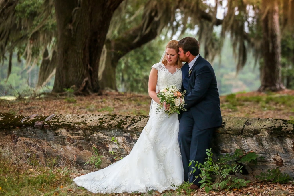 Bride and Groom embrace under a tree.