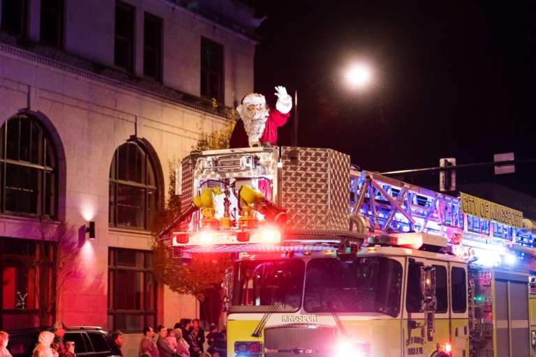 Santa waving from the top of a fire truck during a Christmas Parade.