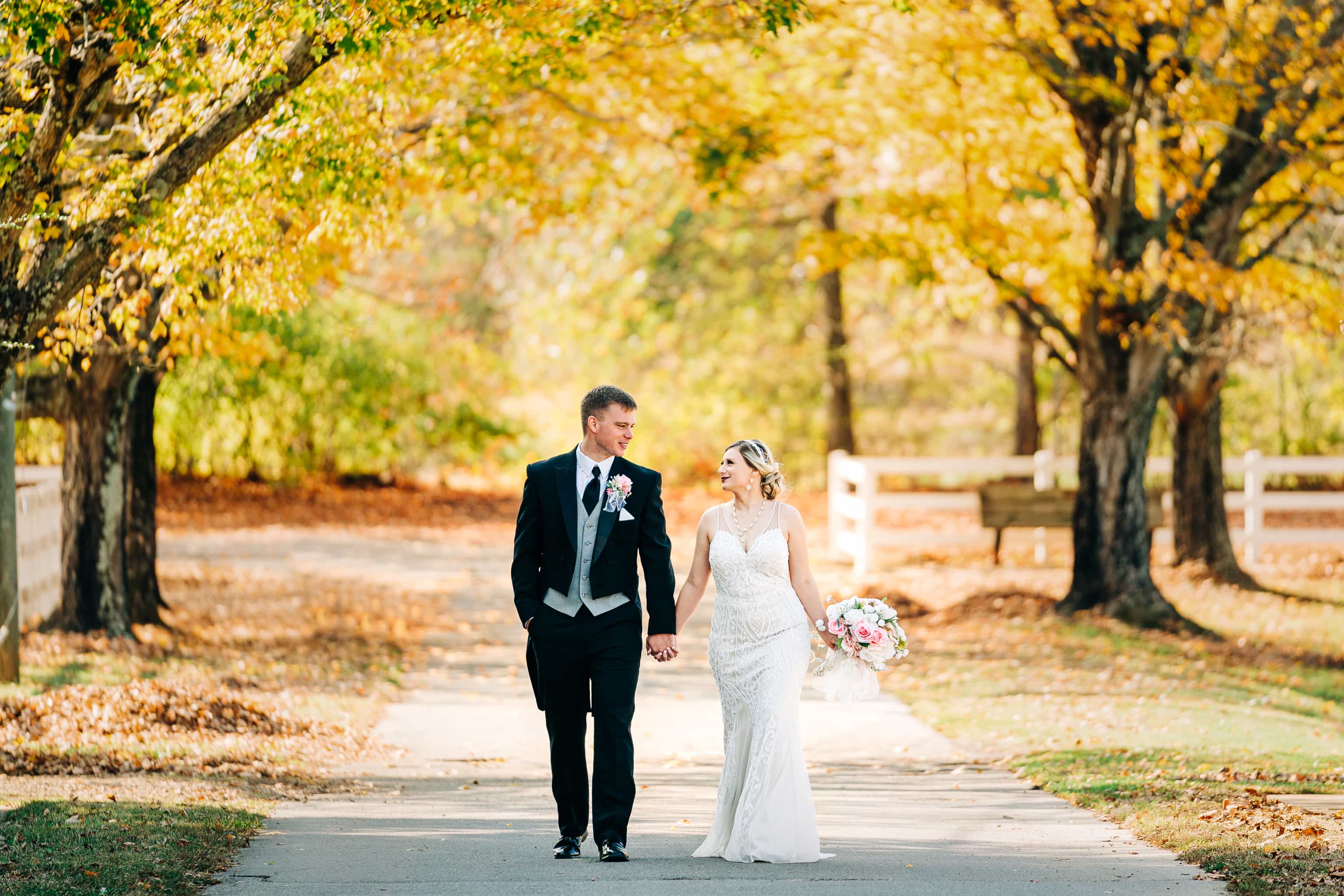 Bride and Groom walking down a road in fall