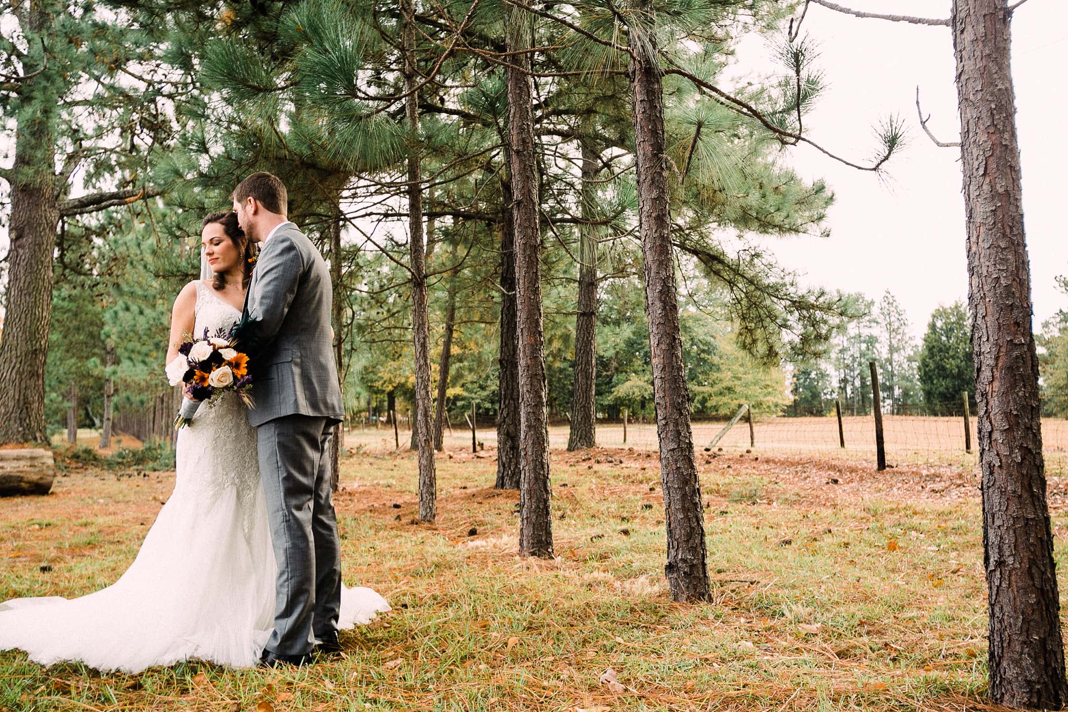 Bride and Groom embrace under pine trees