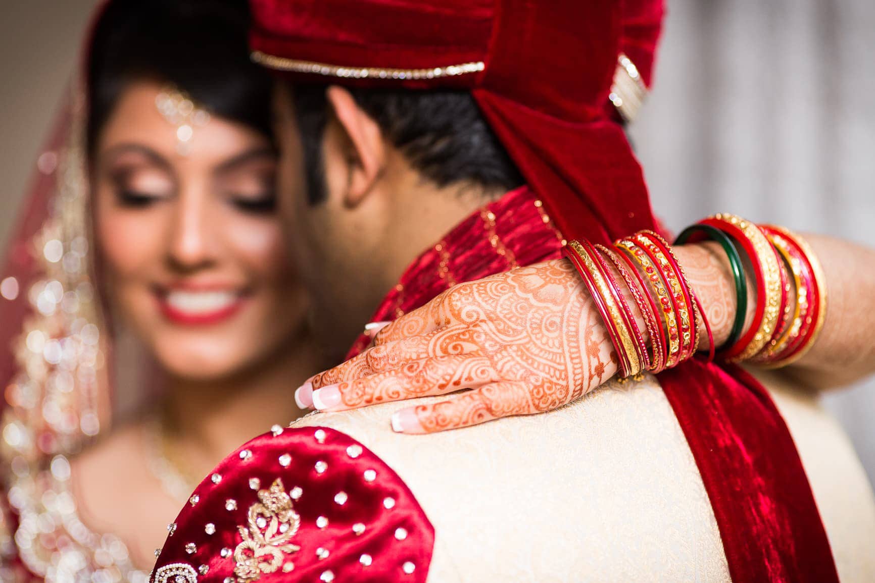 Indian bride smiles while putting her arm around her husband.