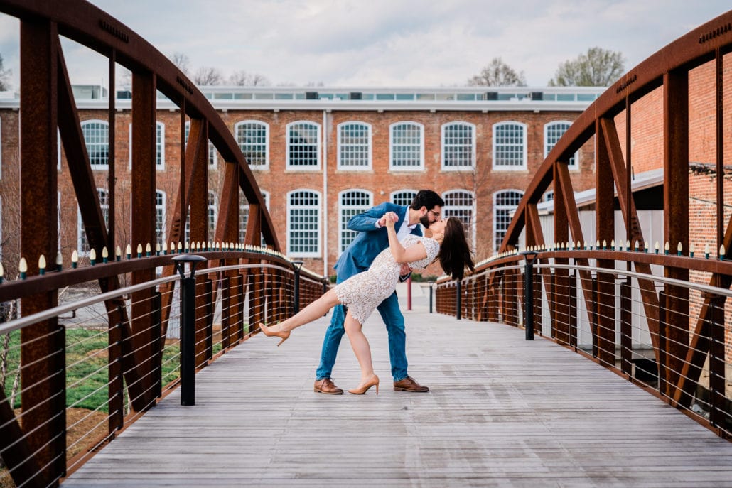Man romantically dips woman on a bridge as they kiss