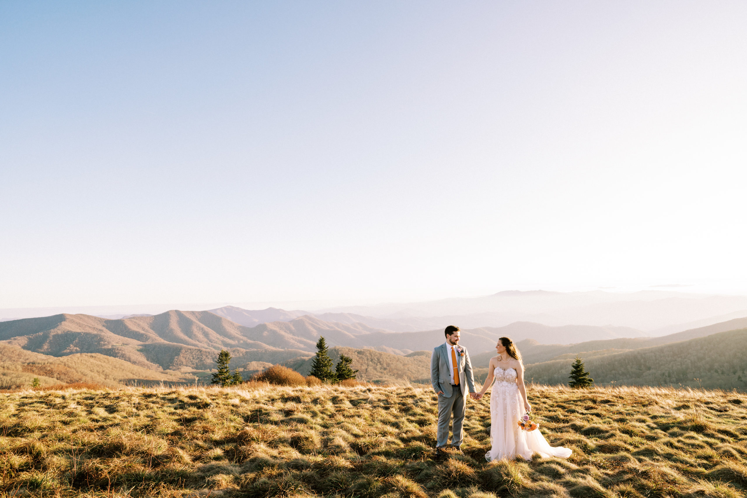 Couple holds hands with beautiful mountain views in the background