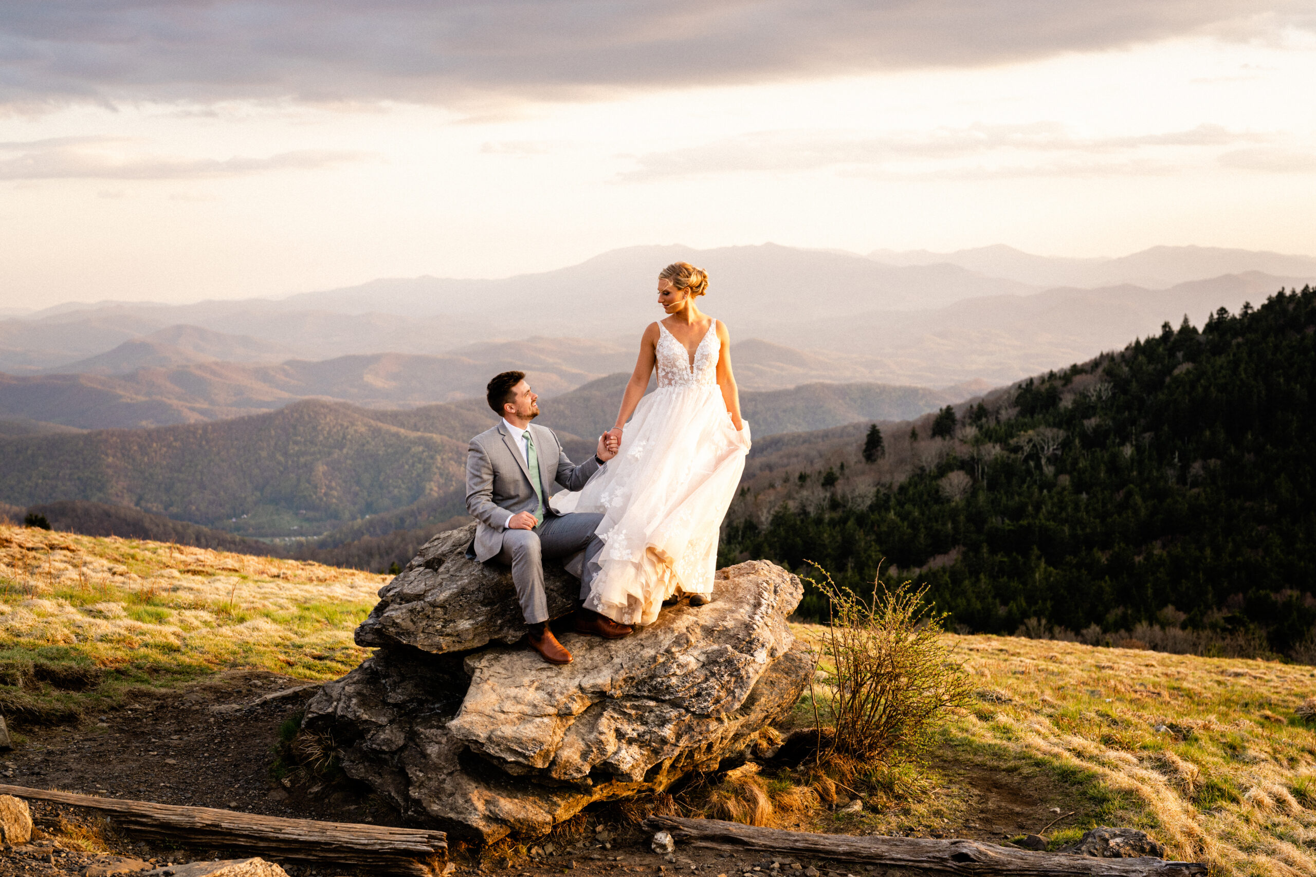 Couple holding hands while standing on a large rock in Roan Mountain